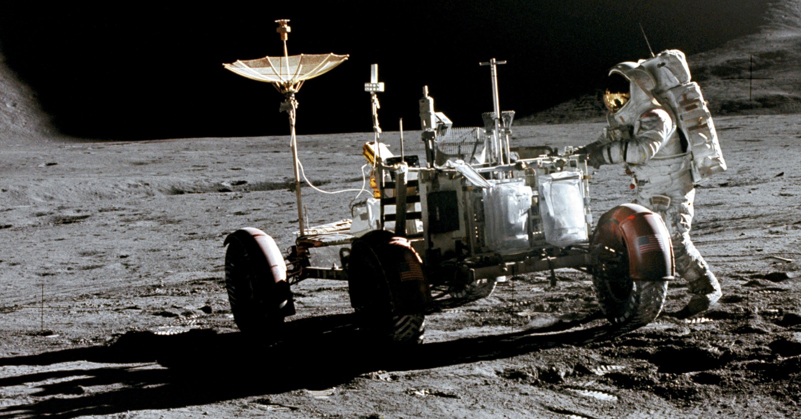 Irwin beside the Apollo 15 rover at the landing site, high-gain antenna raised, EVA 1